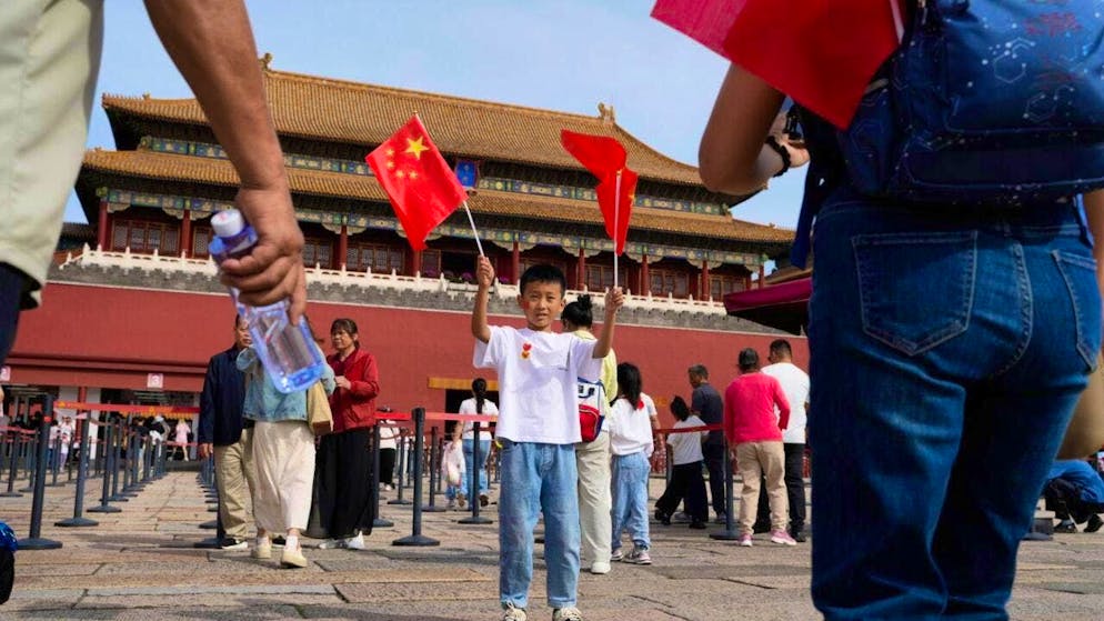 ARCHIVE - A child poses for photos with Chinese national flags in front of the Forbidden City during National Day. Photo: Ng Han Guan/AP/dpa