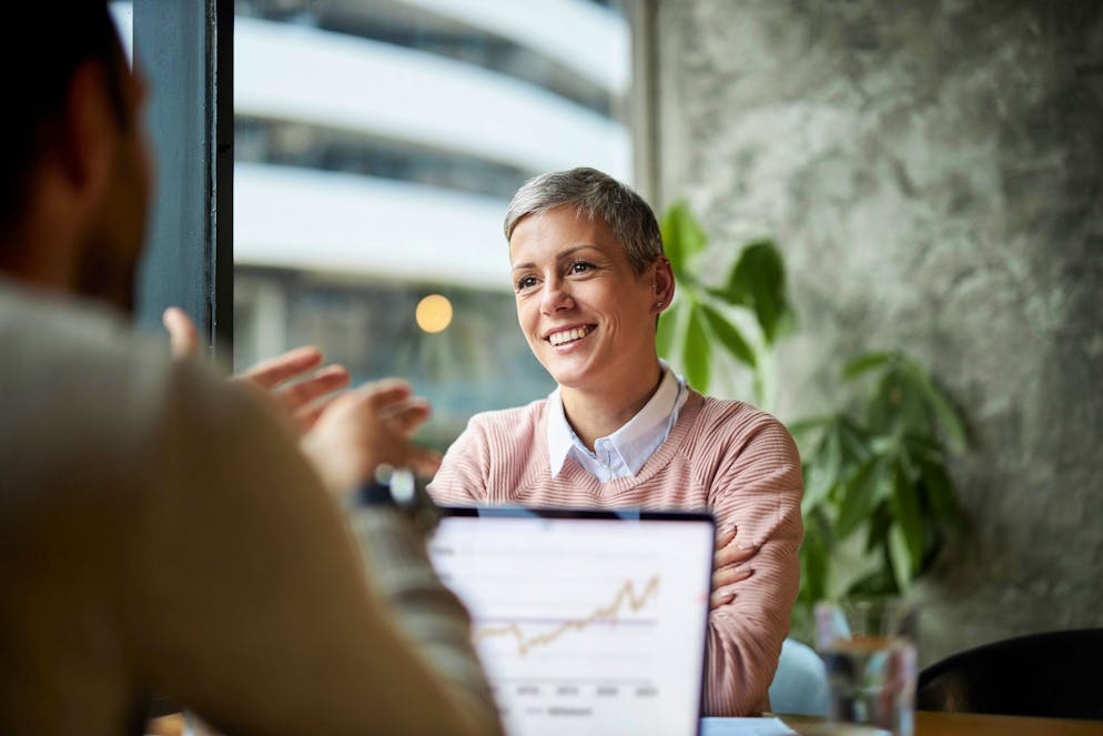 Happy female entrepreneur communicating with her colleague on a meeting in a café.