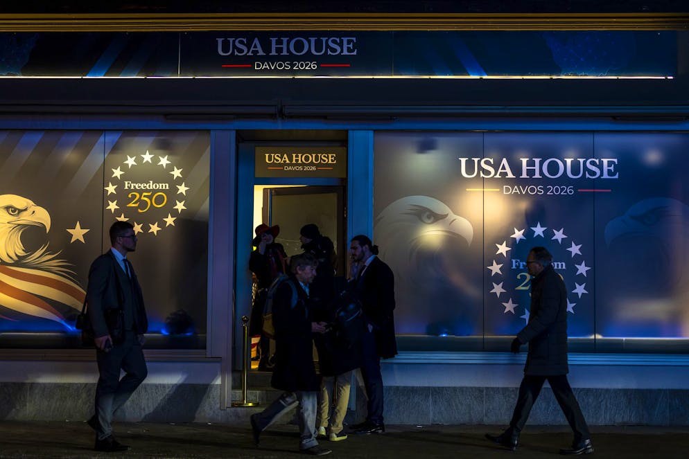 Des passants devant la vitrine d'une boutique de la USA House sur la promenade lors de la 56e réunion annuelle du Forum économique mondial (WEF) à Davos, en Suisse, le mercredi 21 janvier 2026. La réunion, placée sous le thème « L'esprit du dialogue », rassemble des entrepreneurs, des scientifiques, des chefs d'entreprise et des dirigeants politiques à Davos et se déroule du 19 au 23 janvier. (KEYSTONE/Michael Buholzer)