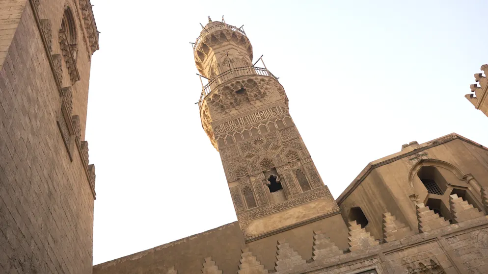 Plötzlich ragt es über den Gassen auf: das Minarett der Madrasa al-Nasir Muhammad. Der Turm von 1303 gehört zum Mamluken-Komplex an der Al-Muʿizz-Strasse und zeigt reich verzierten Stuck sowie ägyptisch-persische Einflüsse.