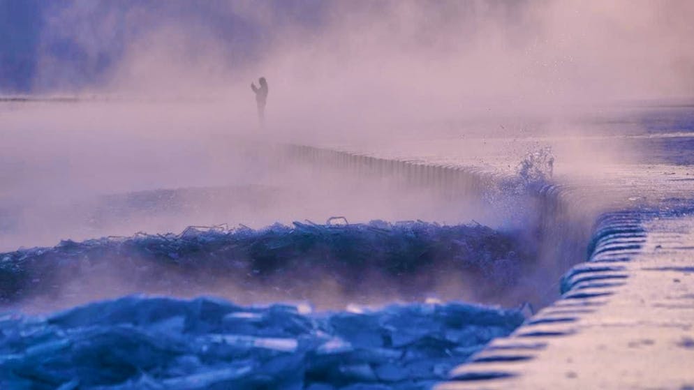 A person walks across an ice-covered beach on the shore of Lake Michigan. Photo: Kiichiro Sato/AP/dpa