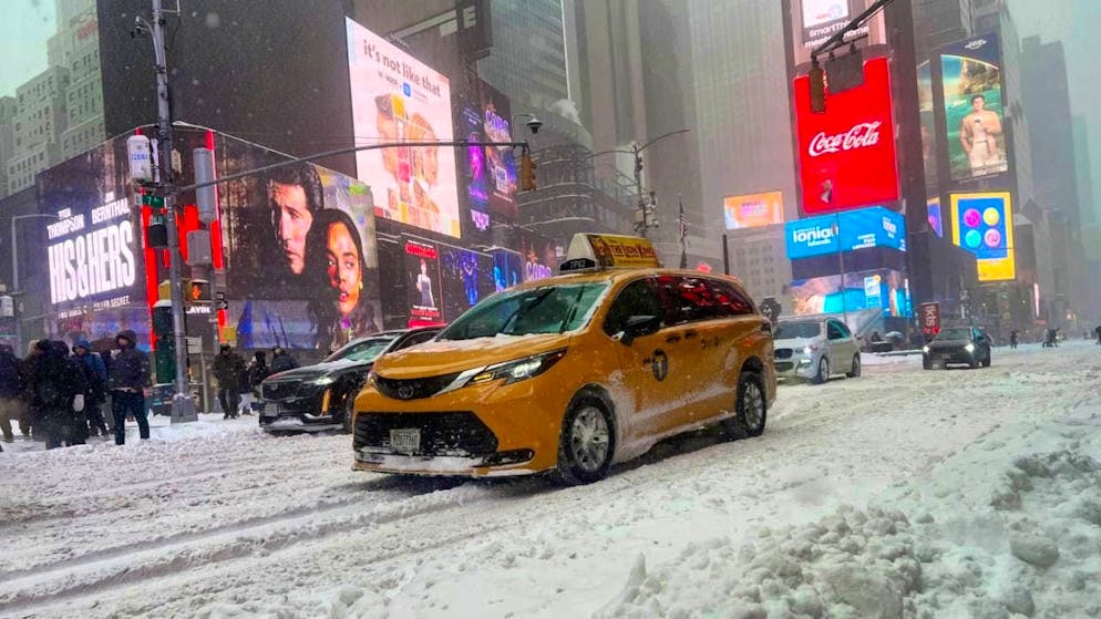 Vehicles drive across a snow-covered street in Times Square. A severe winter storm is currently sweeping across large parts of the USA with freezing cold, snow and ice. Photo: Christina Horsten/dpa