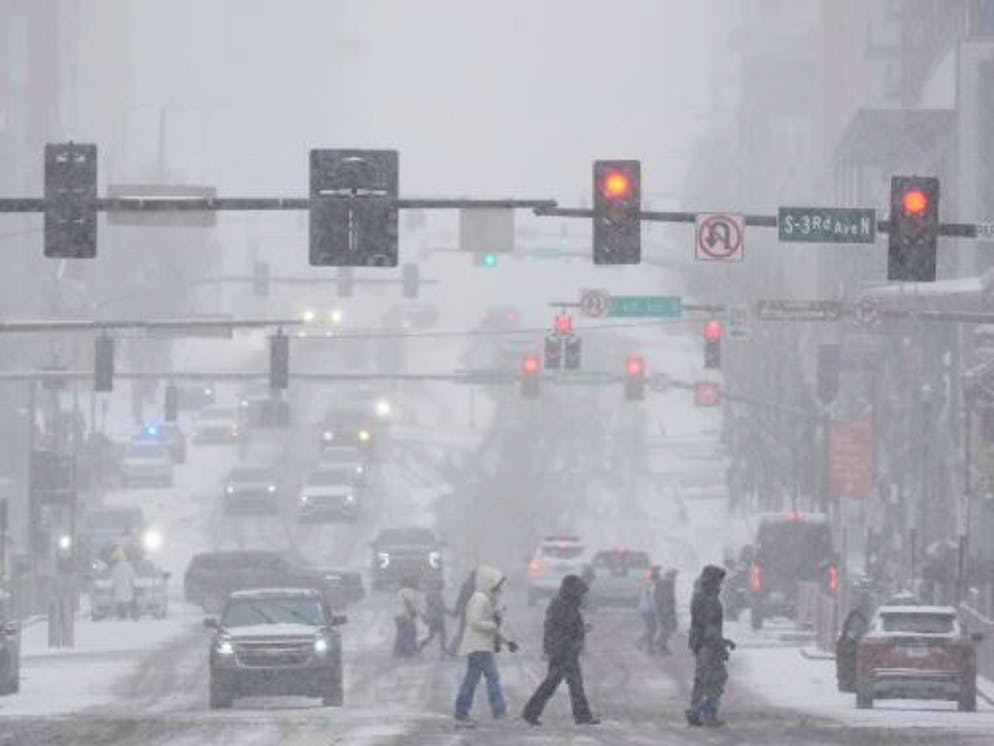 Wintersturm zieht über die USA. Fussgänger überqueren die Strasse am Broadway während eines Wintersturms in Nashville.