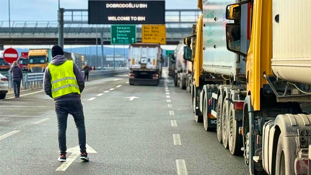 Ein Mann steht neben einer Reihe von Lastwagen und Bussen auf der bosnischen Seite der Grenze zu Kroatien in Svilaj, Bosnien. Foto: Eldar Emric/AP/dpa