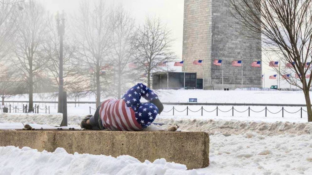 dpatopbilder - A homeless man rests on a warm ventilation shaft for warmth near the Washington Monument. Photo: Mehmet Eser/SOPA Images via ZUMA Press Wire/dpa