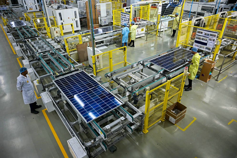 Cette photo prise le 5 novembre 2025 montre des employés inspectant des panneaux solaires sur les chaînes de montage d'une usine du groupe Adani dans la ville portuaire de Mundra, dans l'État du Gujarat. La course à l'énergie verte est lancée. Poussée par une demande en électricité en forte hausse et par la volonté de réduire sa dépendance vis-à-vis de la Chine, l'Inde produit rapidement des panneaux solaires, alimentant un marché en plein essor mais incertain. (Photo de Shammi MEHRA / AFP)