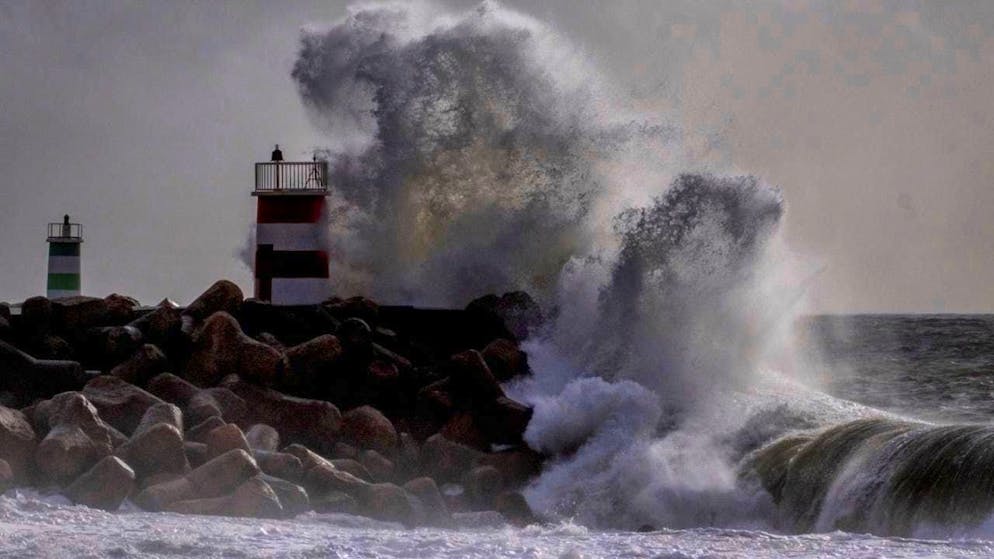 ARCHIVE - Large waves crash against a lighthouse near Nazaré on the coast of Portugal in 2024. Photo: Michael Probst/AP/dpa