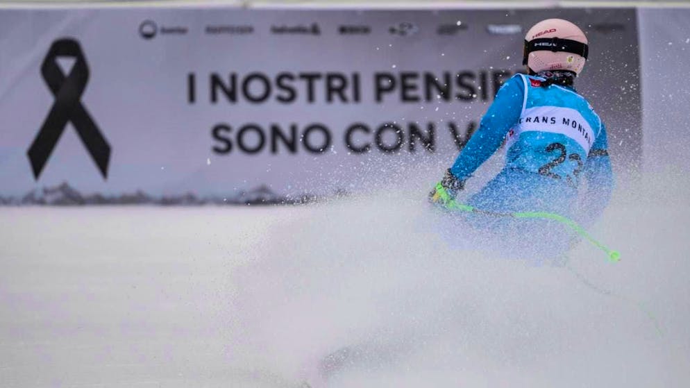 The Italian Elena Curtoni swings in front of the advertising banner with the inscription "Our thoughts are with you" in the finish area in Crans-Montana