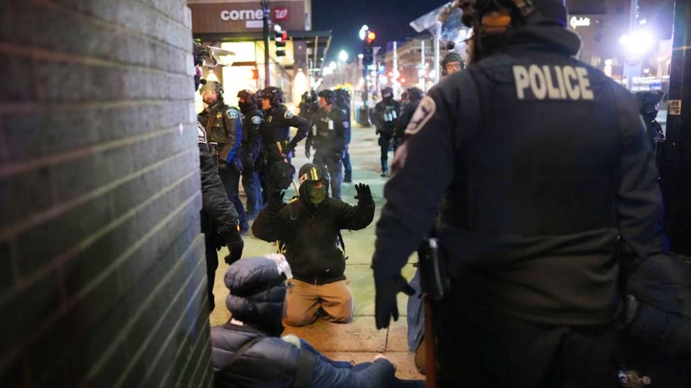 dpatopbilder - Ein Demonstrant hebt auf dem Boden die Arme, während Einsatzkräfte nach der Erklärung einer unerlaubten Versammlung bei einer Lärm-Demonstration vor dem Hotel Graduate by Hilton Minneapolis Festnahmen vornehmen. Foto: Adam Gray/FR172090 AP/AP/dpa