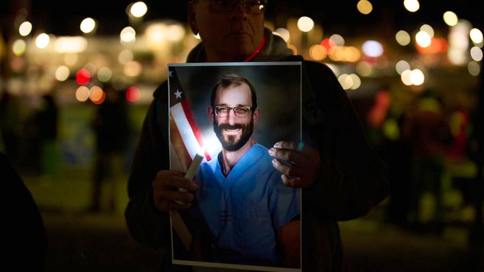 Menschen halten Fotos während einer Mahnwache für Alex Pretti hoch, der von Bundesbeamten in Minneapolis erschossen wurde. Foto: John Locher/AP/dpa