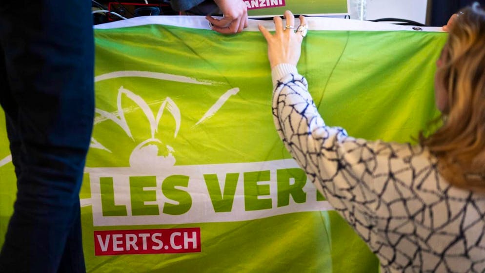 Delegierte hängen ein Transparent am Rednerpult an der Delegiertenversammlung der Grünen Schweiz in Chur auf.