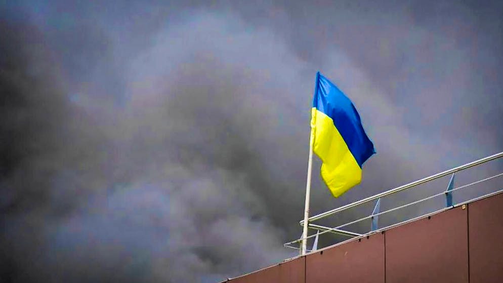 HANDOUT - In this photo released by the Dnipropetrovsk Regional Administration, the Ukrainian flag flies as smoke rises after a Russian missile attack. Photo: Uncredited/Dnipro Regional Administration/AP/dpa