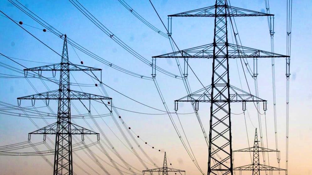 ARCHIVE - Overhead power line pylons stand in a field shortly before sunrise. Photo: Christoph Schmidt/dpa