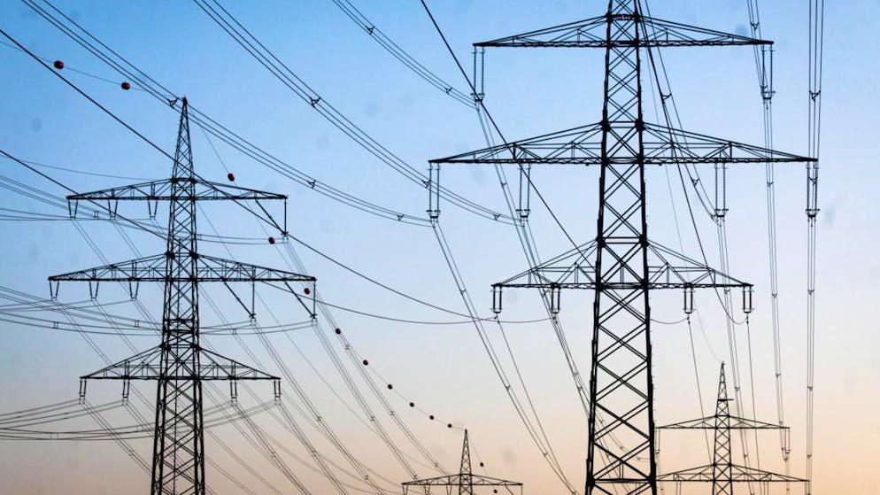 ARCHIV - Freileitungsmasten stehen kurz vor Sonnenaufgang auf einem Feld. Foto: Christoph Schmidt/dpa