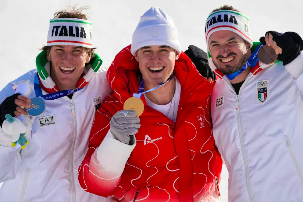 Olimpiadi 2026. Lo svizzero Franjo von Allmen, medaglia d'oro nella discesa libera maschile di sci alpino, al centro, festeggia sul podio accanto all'italiano Giovanni Franzoni, medaglia d'argento, a sinistra, e a Dominik Paris, medaglia di bronzo, mentre arrivano per la cerimonia di consegna delle medaglie alle Olimpiadi invernali 2026, a Bormio, Italia, sabato 7 febbraio 2026. (AP Photo/Rebecca Blackwell)