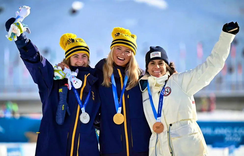 Olimpiadi 2026. La seconda classificata, la svedese Ebba Andersson, la vincitrice, la svedese Frida Karlsson, la terza classificata, la norvegese Heidi Weng, festeggiano durante la cerimonia di consegna delle medaglie dopo la gara di sciathlon 10km+10km delle Olimpiadi invernali di Milano Cortina 2026.