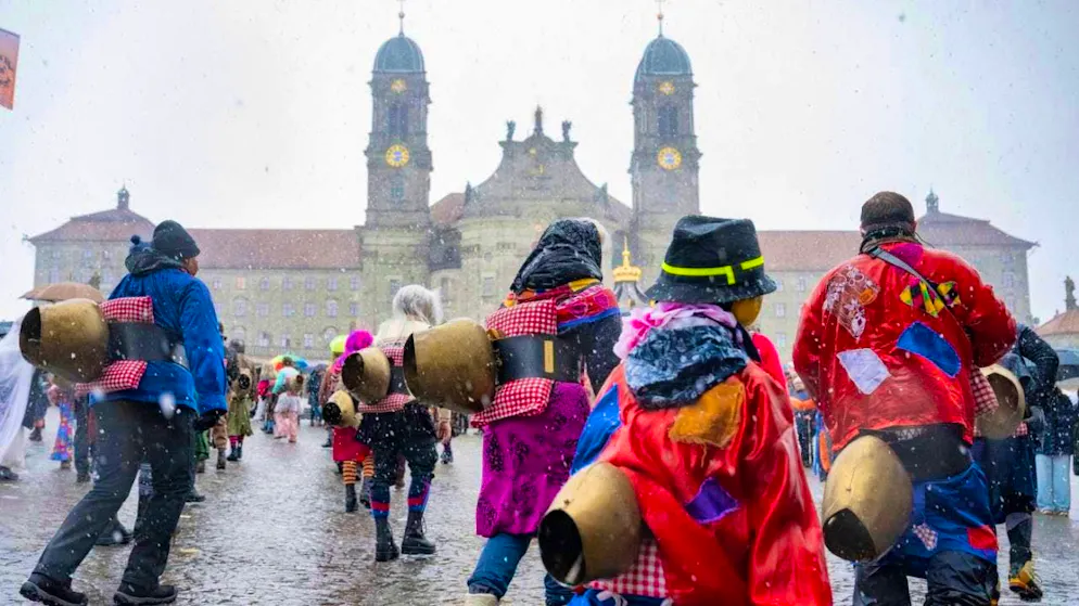 Tüüfel bring the hermits to the carnival at the Sühudiumzug - Gallery. Sühudis with Trychlen populate the square in front of the Benedictine monastery in Einsiedeln.