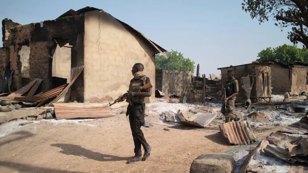 ARCHIV - Soldaten patrouillieren vor niedergebrannten Häusern. Bewaffnete haben bei einem Angriff in Nigeria Dutzende Menschen getötet. Foto: Pelumi Salako/AP/dpa/Archivbild