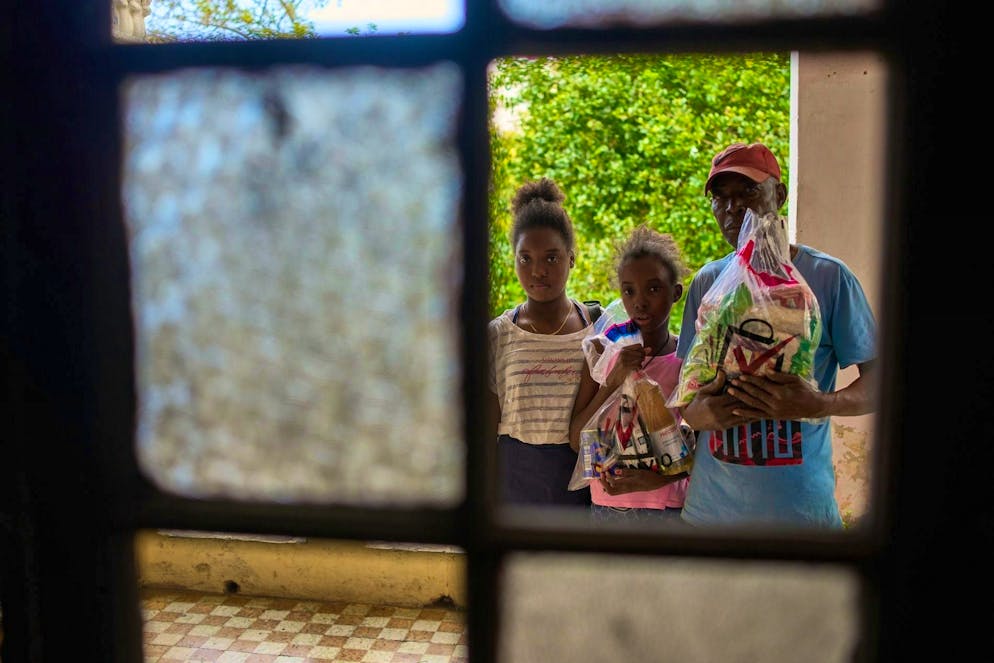 A father and his two daughters pick up donated food in Havana.