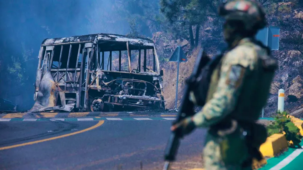 dpatopbilder - A soldier stands next to a burnt-out bus that was set on fire in Cointzio after the death of "El Mencho". Photo: Armando Solis/AP/dpa