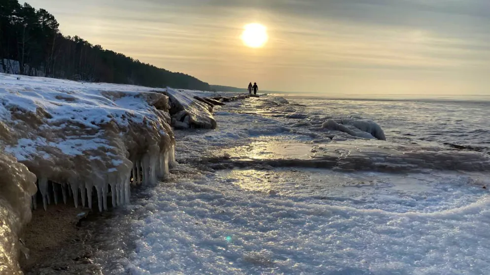 ARCHIV - Spaziergänger gehen am Strand der teilweise zugefrorenen Ostsee entlang. Foto: Alexander Welscher/dpa