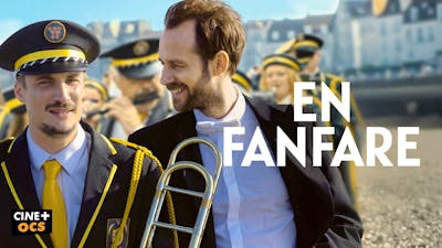 Zwei Männer stehen lächelnd in farbenfrohen Fantasie-Uniformen nebeneinander auf dem sonnigen Filmplakat zu En Fanfare.