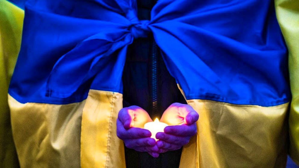 A person holds a candle at a rally to mark the fourth anniversary of the Russian invasion of Ukraine. Photo: Boris Roessler/dpa