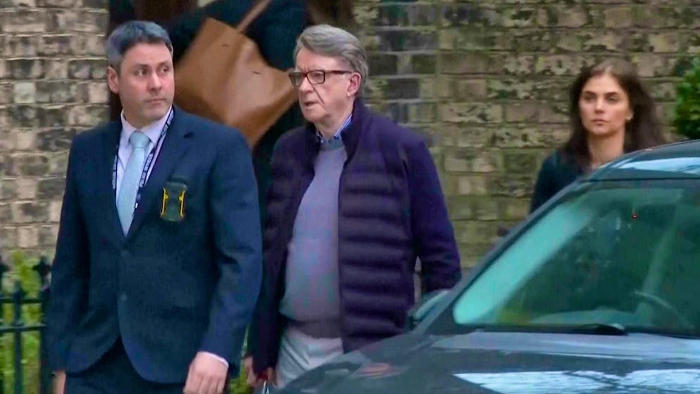 Peter Mandelson (center) is escorted to a car in London on Monday.