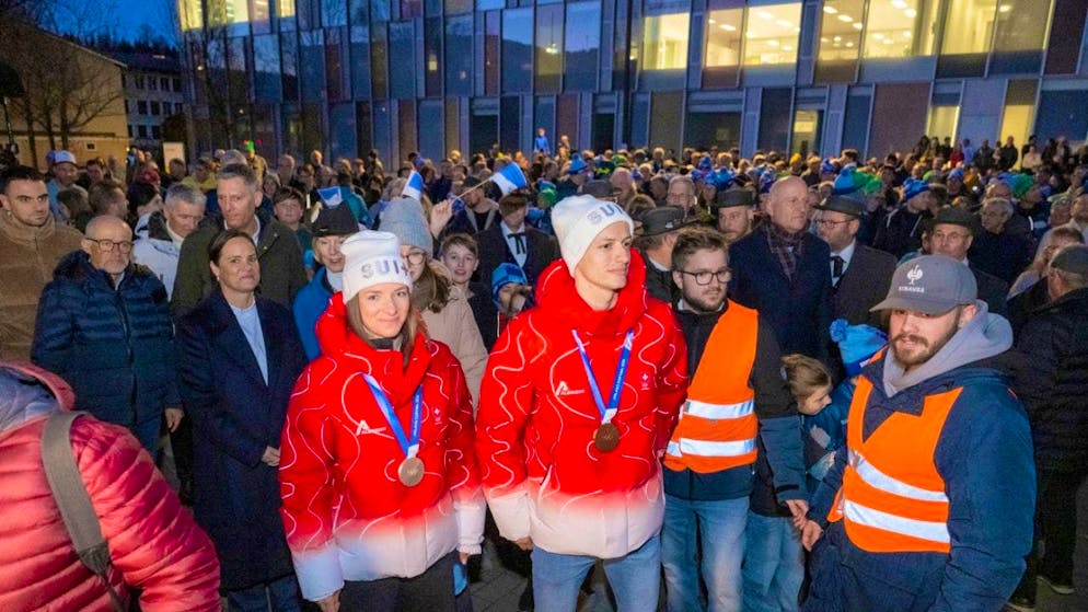 Nadine Fähndrich (left) and Gregor Deschwanden with their Olympic medals as they enter the multi-purpose hall in Horw, where they belong to the ski club.