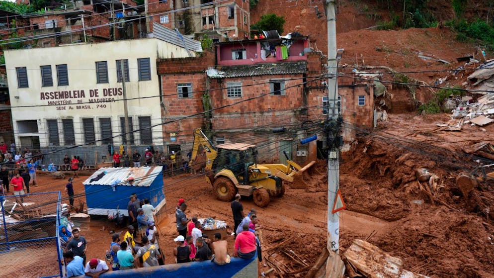 Feuerwehrleute und Mitarbeiter des Zivilschutzes helfen im brasilianischen Bundesstaat Minas Gerais an der Stelle, an der Häuser aufgrund von heftigen Regenfällen und Überschwemmungen in Juiz de Fora eingestürzt sind. Foto: Silvia Izquierdo/AP/dpa
