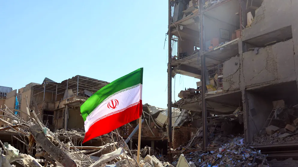 Drapeau national iranien placé à côté d'un bâtiment endommagé près de la place Ferdowsi après une frappe aérienne dans le centre de Téhéran le 03 mars 2026 (Illustration).