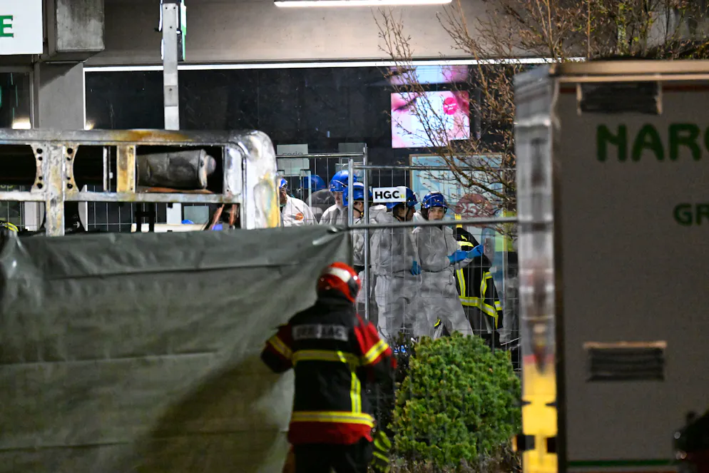 Weiss gekleidete Forensiker*innen beim ausgebrannten Postauto.