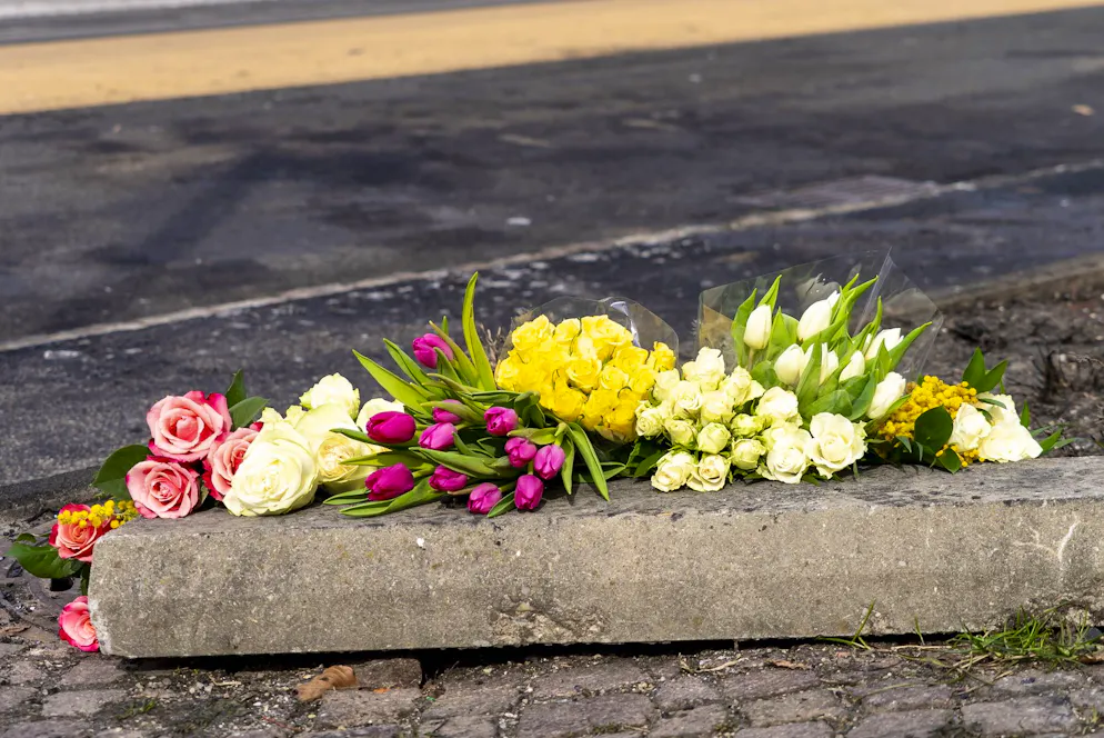 Beim Brandort legen Menschen Blumen nieder, um der Opfer zu gedenken.