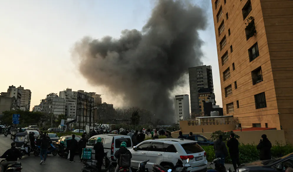 Des gens regardent un panache de fumée monter après une frappe de missile israélien dans le quartier de Bashoura, au centre de Beyrouth, le 12 mars 2026.L'armée israélienne a dit avoir lancé une série de frappes à Beyrouth le 12 mars, après avoir prévenu les habitants d'un quartier du centre de la capitale libanaise qu'elle allait viser un bâtiment là-bas.