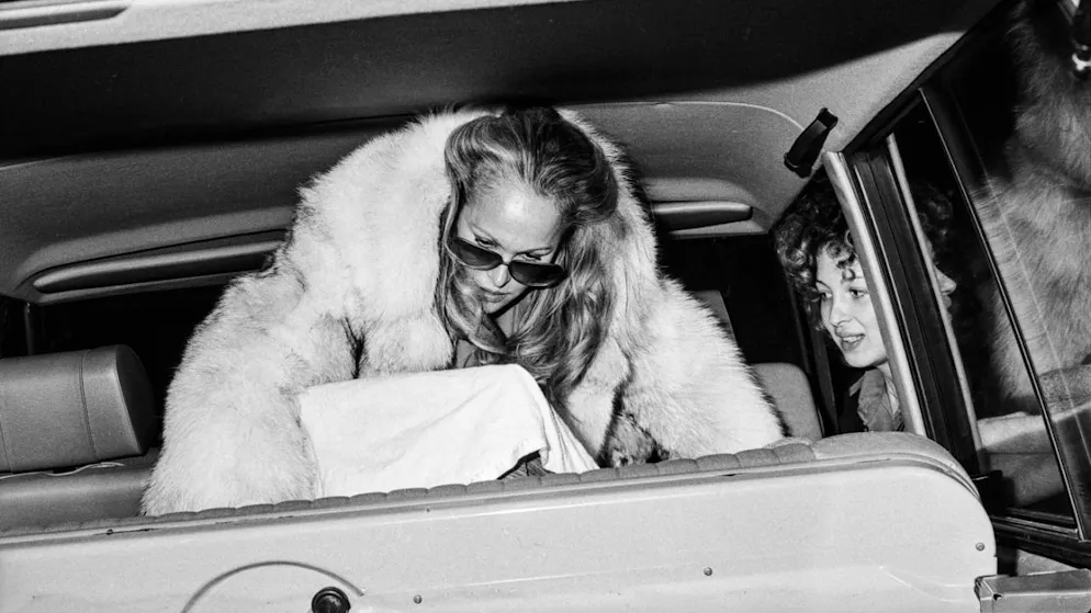 Ursula Andress en décembre 1980 à son arrivée à l'aéroport de Zurich-Kloten. Elle tient sur ses genoux son fils alors âgé de six mois.