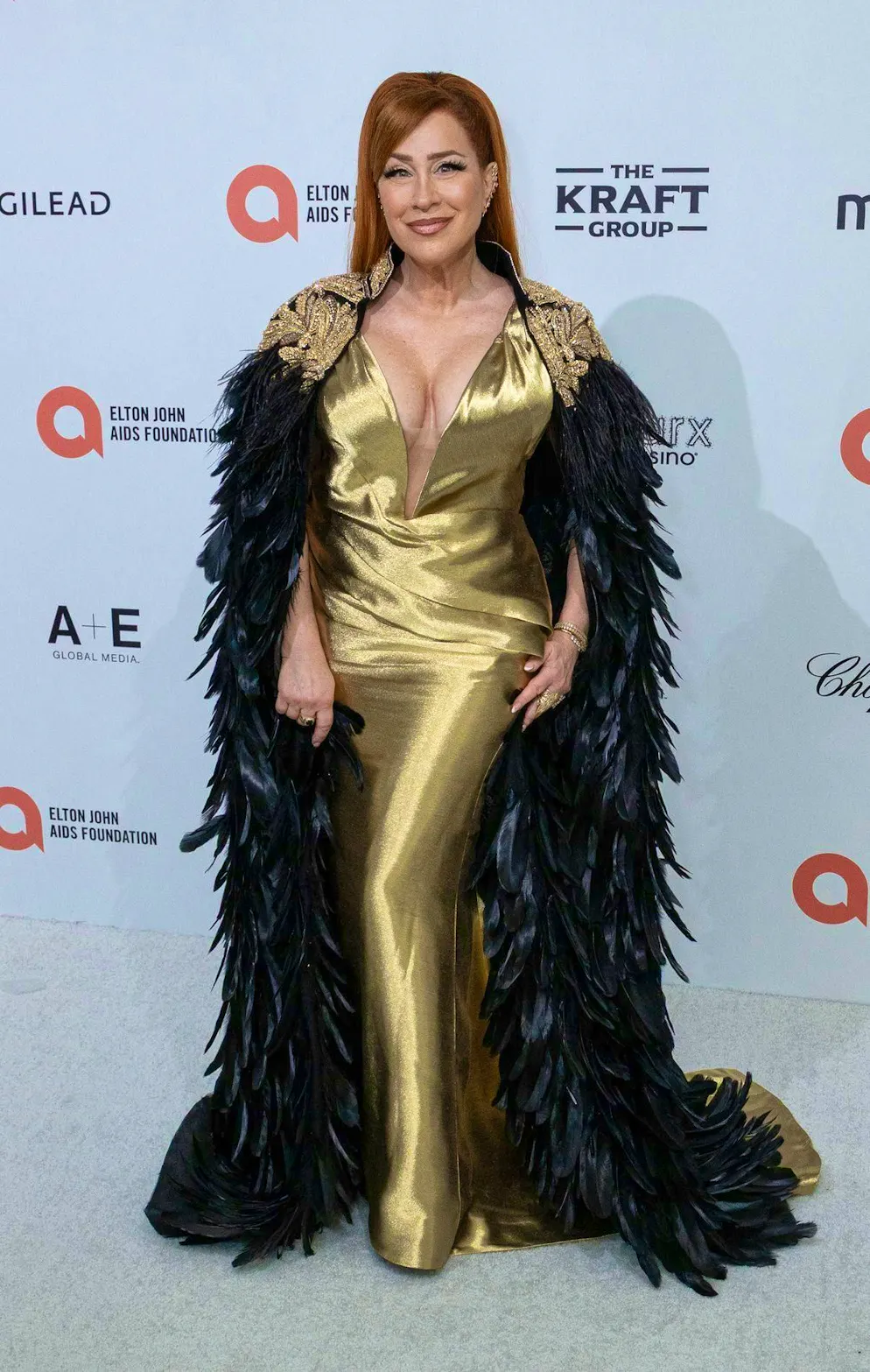 Les Oscars 2026 : Les meilleures tenues du tapis rouge. Le minimalisme n’est pas son fort : Lisa Ann Walter suit certes la tendance des plumes, mais associée à sa robe dorée, le look frôle presque le théâtral.