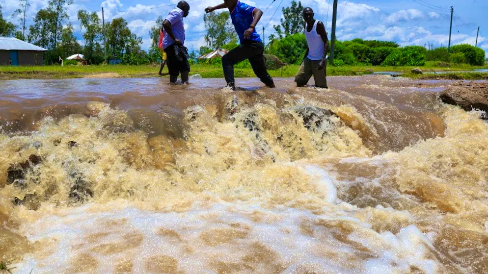 People cross a flooded section of road after heavy rains in Kenya. Photo: Andrew Kasuku/AP/dpa