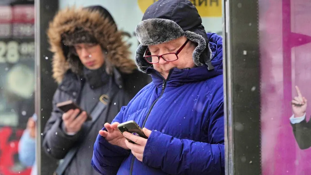 ARCHIVE - People look at their smartphones at a bus stop in St. Petersburg. Photo: Dmitry Lovetsky/AP/dpa/Archive image