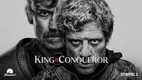 Zwei Krieger in mittelalterlicher Rüstung stehen sich vor einer historischen Kulisse gegenüber. Historien-Serie King and Conqueror.