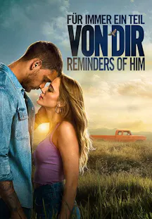 Ein Mann und eine Frau stehen sich in einem Feld bei Sonnenuntergang gegenüber und berühren sich fast mit der Stirn. Im Hintergrund ist ein orangefarbener Pickup-Truck in einer weiten Landschaft zu sehen.