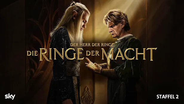 Zwei Elben stehen sich im Profil gegenüber. Der rechte Elb hält schimmernde Ringe in seinen Handflächen, die er dem linken Elben präsentiert. Ein Lichtstrahl fällt von oben auf die Szene. Im Zentrum steht der goldene Schriftzug des Titels.