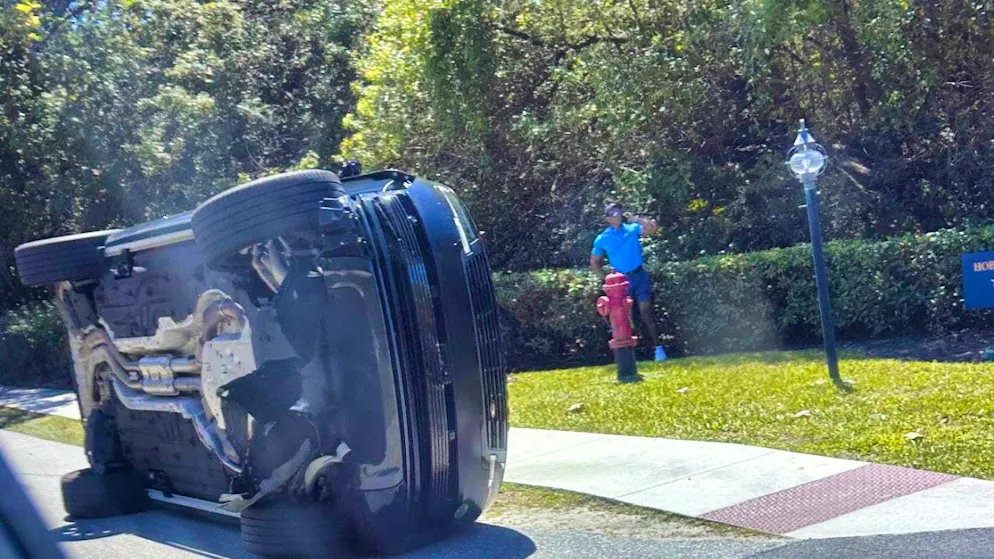 Tiger Woods stands uninjured next to the car in which he was previously involved in an accident