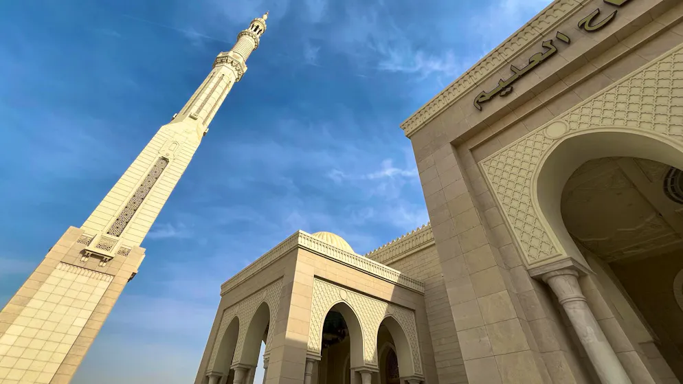 Mosque. Detail of stone and sky: the intricate decorations on the minaret and façade show how strongly the architecture is based on classic Islamic forms - only one size larger, more massive, more stately.