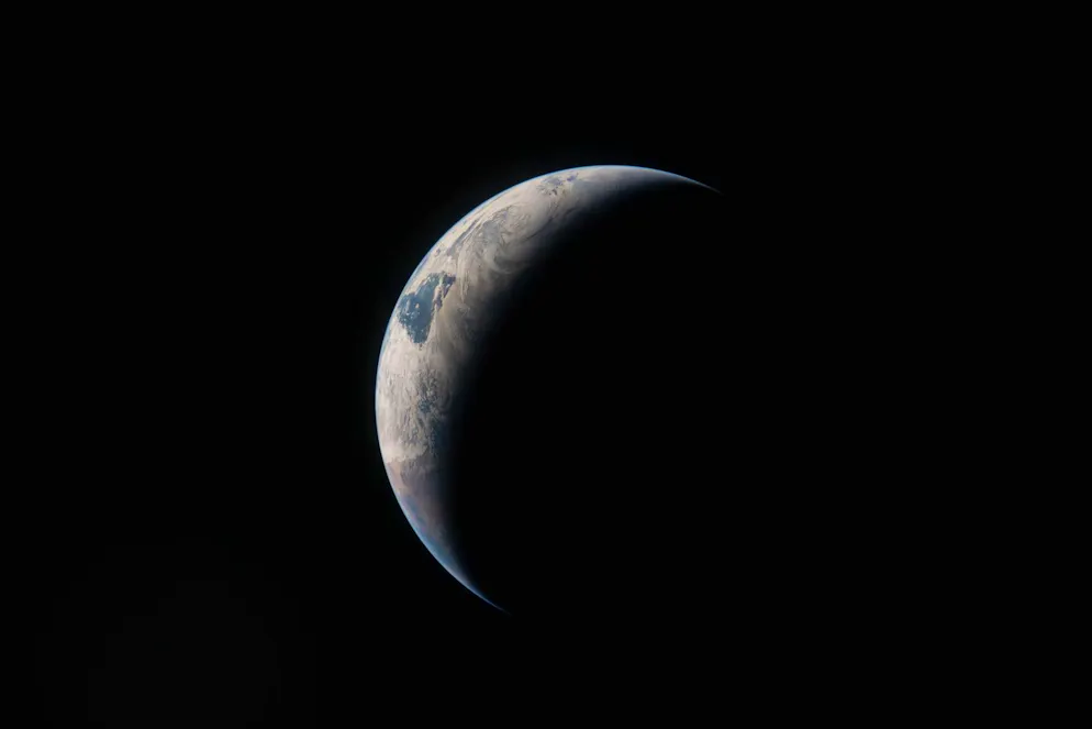 Im Sonnenlicht zeichnet sich ein feiner Bogen der Erde ab, während der restliche Planet im Dunkel des Alls verschwindet.