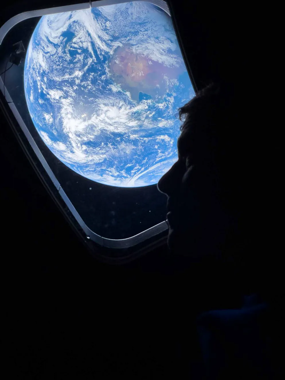 Artemis‑II‑Kommandant Reid Wiseman blickt durch das Hauptfenster der Orion‑Raumkapsel zurück auf die Erde – auf dem Weg zum Mond.