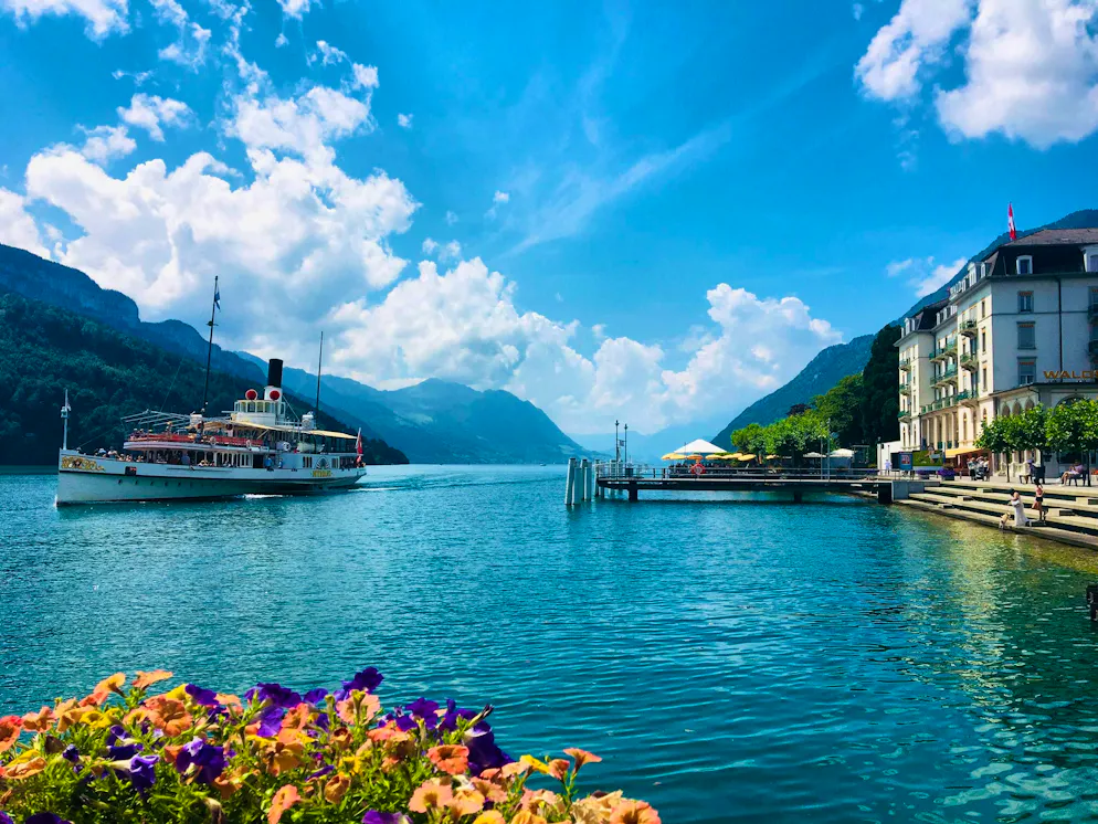 Idées d'excursions CFF - Printemps 2026 - Luzern. Un véritable paysage de carte postale suisse: bateau à vapeur sur le lac des Quatre-Cantons devant le port de Brunnen.