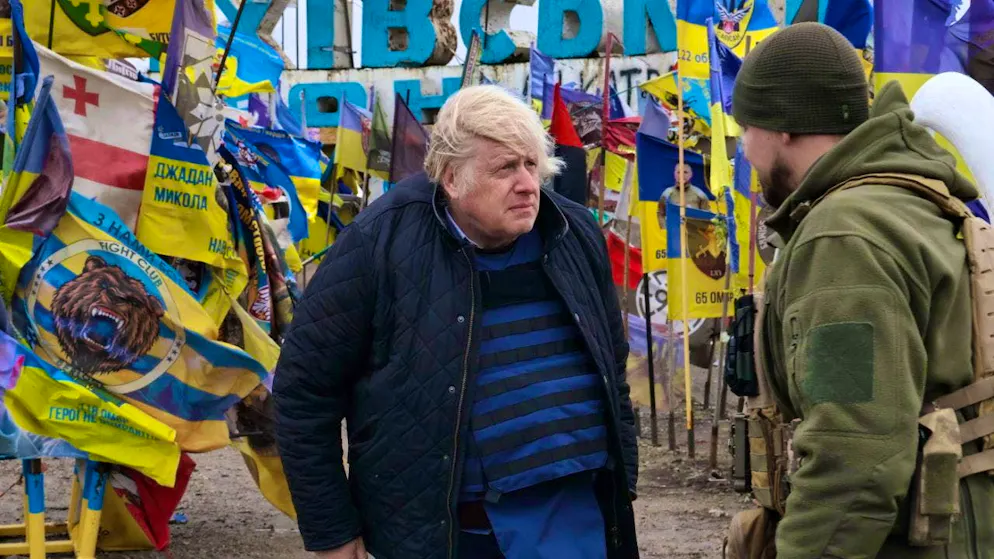 HANDOUT - In this photo released by the press service of the 65th Mechanized Brigade of Ukraine via AP, former British Prime Minister Boris Johnson speaks with a Ukrainian soldier at the entrance sign to the village, surrounded by Ukrainian national flags and flags of military units. Photo: Andriy Andriyenko/Ukrainian 65 Mechanized brigade/AP/dpa - ATTENTION: For editorial use only in connection with current reporting and only with full attribution of the above credit