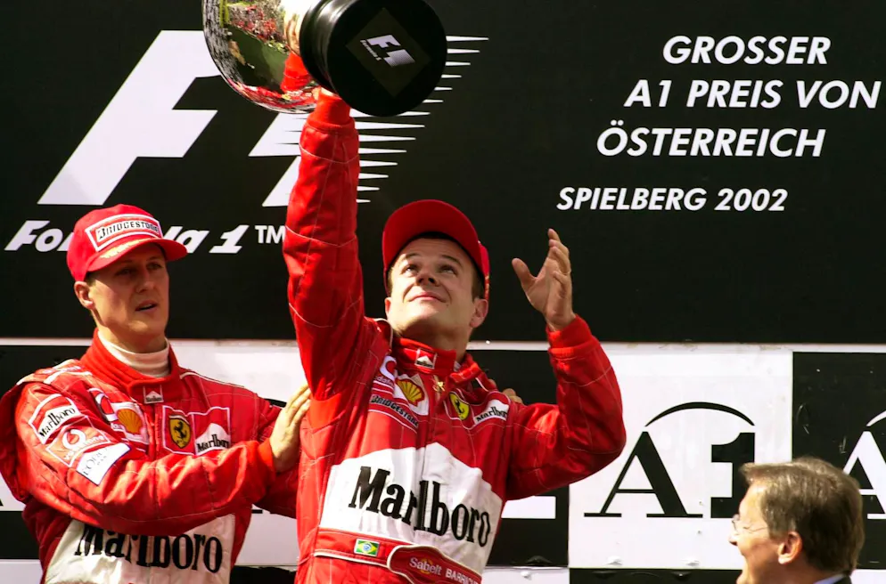 Schumi überlässt Rubens Barrichello den Siegerpokal nach dem kontroversen Finish beim Grossen Preis von Österreich 2002.
