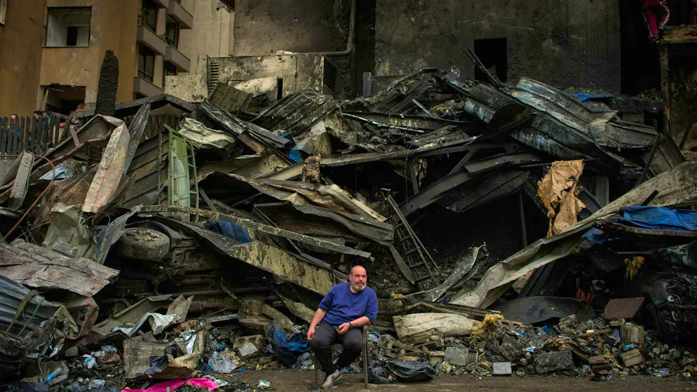 A man sits in front of the charred rubble of a building destroyed in an Israeli airstrike in Beirut (April 10, 2026.