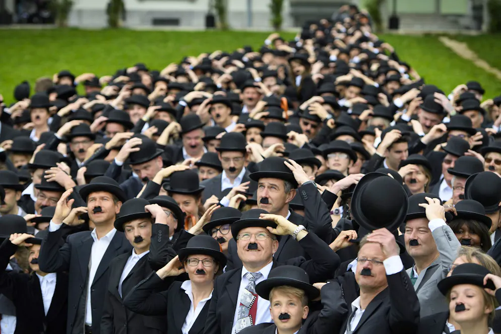 Quelque 662 personnes déguisées en Charlie Chaplin posent pour une photo de groupe devant le Manoir de Ban lors d'une tentative de rassemblement record du plus grand nombre de personnes déguisées en Charlot, à l'occasion de l'anniversaire de Charlie Chaplin et pour célébrer la première année d'existence du musée « Chaplin's World by Grévin », à Corsier, au-dessus de Vevey, en Suisse, le dimanche 16 avril 2017. En juin prochain, le lieu devrait à nouveau accueillir une tentative de record du monde du plus grand rassemblement de Charlots.